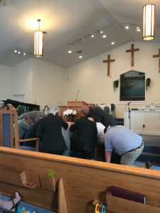 Praying around Steve at ordination service.