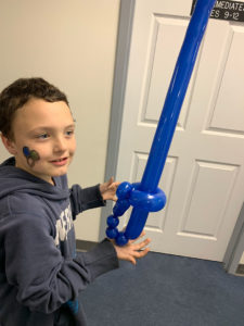 Child holding a blue balloon sword.