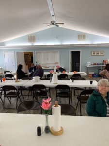 Church members talking in background of fellowship hall.